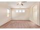 Light-filled main bedroom with a neutral palette, multiple windows, and connecting door to the ensuite bathroom at 17458 W Wandering Creek Rd, Goodyear, AZ 85338
