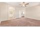 Spacious main bedroom with a ceiling fan, archway to the ensuite, and an open doorway to the hallway at 17458 W Wandering Creek Rd, Goodyear, AZ 85338