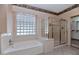 Bathroom complete with a soaking tub, glass block window, and separate glass-enclosed shower, promoting relaxation at 17806 N Becke Ln, Surprise, AZ 85374