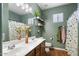 Bathroom with double sinks, wooden vanity, large mirror, and green-painted walls at 18237 W Port Au Prince Ln, Surprise, AZ 85388