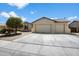 Inviting single-story home with a three-car garage, mature trees, and a concrete driveway at 18237 W Port Au Prince Ln, Surprise, AZ 85388