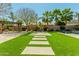 A manicured backyard shows palm trees, artificial turf, and a wooden pergola at 18483 W Paradise Ln, Surprise, AZ 85388