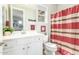Charming bathroom with white vanity, decorative mirror, and a striped shower curtain at 18483 W Paradise Ln, Surprise, AZ 85388
