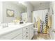 Bright bathroom with double vanity, white cabinets, and a yellow and grey shower curtain at 18483 W Paradise Ln, Surprise, AZ 85388
