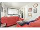 Living room area featuring a large red couch, wall decor, and carpet flooring at 18483 W Paradise Ln, Surprise, AZ 85388