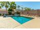 A sparkling pool surrounded by desert landscaping and palm trees for a backyard oasis at 18483 W Paradise Ln, Surprise, AZ 85388