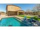A backyard pool with tanning ledge and waterfall feature shows chairs partially submerged in clear blue water at 18483 W Paradise Ln, Surprise, AZ 85388