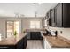 Open kitchen featuring black cabinetry, stainless steel appliances, and countertops, with modern lighting at 43724 W Cowpath Rd, Maricopa, AZ 85138