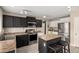 Well-lit kitchen boasts stainless appliances, an island with seating and dark cabinets with light counters at 43724 W Cowpath Rd, Maricopa, AZ 85138