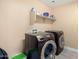 Laundry room with newer front loading washer and dryer units and white shelving at 43724 W Cowpath Rd, Maricopa, AZ 85138