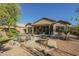 Backyard with a covered patio, a dining set, a desert landscape, and a built-in stone fire pit at 4415 W Ellis St, Laveen, AZ 85339