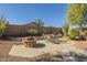Scenic backyard featuring a dining set, a built-in stone fire pit, and mature desert landscaping at 4415 W Ellis St, Laveen, AZ 85339