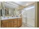Bathroom featuring double sinks, a large mirror with vanity lighting, and a glass-enclosed shower at 4415 W Ellis St, Laveen, AZ 85339