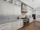 Gourmet kitchen showcasing custom white cabinetry, stainless steel appliances, and luxurious marble backsplash at 6129 E Turquoise Ave, Paradise Valley, AZ 85253