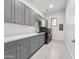 Modern laundry room with grey cabinetry, white countertops, and stainless steel appliances at 6129 E Turquoise Ave, Paradise Valley, AZ 85253