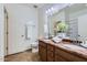 Bathroom with double sinks, granite counters, decorative white flowers, and ceramic tile flooring at 7589 W Quail Track Dr, Peoria, AZ 85383