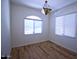 Bright bedroom with wood-look flooring, two windows, and stylish chandelier at 7589 W Quail Track Dr, Peoria, AZ 85383
