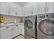 Functional laundry room with ample cabinet space, a utility sink and modern appliances at 8154 E Jaeger St, Mesa, AZ 85207
