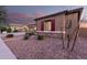 This home features charming desert landscaping, a rock facade, and striking red shutters and trim at 19011 E Carriage Way, Queen Creek, AZ 85142