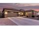 Inviting home with a three-car garage, desert landscaping, and warm exterior lighting at 19011 E Carriage Way, Queen Creek, AZ 85142