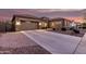 Inviting home with a three-car garage, desert landscaping, and warm exterior lighting at 19011 E Carriage Way, Queen Creek, AZ 85142