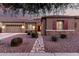 Attractive single-story home featuring stone details, low-maintenance desert landscaping, and a welcoming red door at 19011 E Carriage Way, Queen Creek, AZ 85142