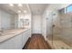 Bright bathroom features double sinks, quartz countertop, dark wood floors, and a glass shower at 21277 N 272Nd Ave, Buckeye, AZ 85396