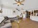 Open-concept living room with a large sectional sofa, modern ceiling fan, and elegant wood-look tile flooring at 1347 W Straford Ave, Gilbert, AZ 85233