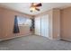Cozy bedroom featuring plush carpeting, a ceiling fan, a window with views, and a closet with sliding doors at 1520 E Flint St, Chandler, AZ 85225