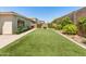 Well-maintained backyard with artificial turf, paver walkway, flowering bushes, and block wall fencing at 5962 E Abraham Ln, Phoenix, AZ 85054