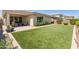 A beautiful outdoor oasis with manicured landscaping, a patio area, and lush synthetic lawn at 5962 E Abraham Ln, Phoenix, AZ 85054