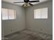 This neutral bedroom features neutral carpet, two windows and a ceiling fan at 6258 E Duncan St, Mesa, AZ 85205