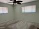 A bright bedroom features neutral carpet, two windows and a ceiling fan at 6258 E Duncan St, Mesa, AZ 85205