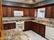 This kitchen features granite counters, cherry cabinets, white appliances and tile flooring at 6258 E Duncan St, Mesa, AZ 85205