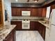 This kitchen features granite counters, cherry cabinets, white appliances and tile flooring at 6258 E Duncan St, Mesa, AZ 85205