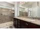 Bathroom featuring a double vanity, dark wood cabinetry and a glass shower with marble-style tile at 10363 W Rosewood Ln, Peoria, AZ 85383