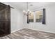 Bright dining room features a modern chandelier, wood-style tile floors, and beautiful barn door at 10363 W Rosewood Ln, Peoria, AZ 85383