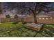 This backyard features a lush lawn, a playset, string lights, and a beautiful mature tree with a wooden deck at 10775 W Davis Ln, Avondale, AZ 85323