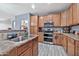 Well-equipped kitchen with stainless steel appliances, wood cabinets, granite countertops, and tile backsplash at 10775 W Davis Ln, Avondale, AZ 85323