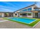 Beautiful backyard with a modern pool, an outdoor dining area, a covered patio, gravel landscaping, and green turf at 11649 N Miller Rd, Scottsdale, AZ 85260