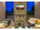 Outdoor living space with gas fireplace, a TV, brick accents, comfortable seating, and a decorative glass coffee table at 11649 N Miller Rd, Scottsdale, AZ 85260