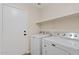 Functional laundry area with modern washer and dryer units, and built in storage shelving at 16585 W Tonto St, Goodyear, AZ 85338