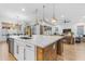 Kitchen island with white marble countertop, wooden base, sink, and modern lighting at 21325 S 201St Way, Queen Creek, AZ 85142