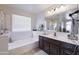 Bright bathroom features a soaking tub and vanity with dark wood cabinets and modern lighting at 31918 N Caspian Way, San Tan Valley, AZ 85143