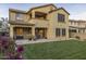 Spacious backyard featuring lush green lawn, covered patio, and tan stucco two-story home at 3911 E Rockingham Rd, Phoenix, AZ 85050