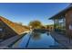 Community lap pool with tiled pool bottom, nearby chairs, stone wall, and nearby desert vegetation at 3911 E Rockingham Rd, Phoenix, AZ 85050