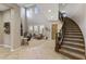 Bright living room featuring high ceilings, large windows, a fireplace, and a curved staircase at 3911 E Rockingham Rd, Phoenix, AZ 85050