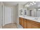 A bathroom with double sinks, wood cabinets, and tile floor at 40613 N Jerlyn Pl, San Tan Valley, AZ 85140