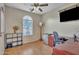 Bright bedroom features a ceiling fan, window, and a modern entertainment setup with a mini-fridge at 40613 N Jerlyn Pl, San Tan Valley, AZ 85140