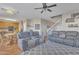 Comfortable living room showcasing gray sofas, ceiling fan, and open floor plan to the kitchen and staircase at 40613 N Jerlyn Pl, San Tan Valley, AZ 85140